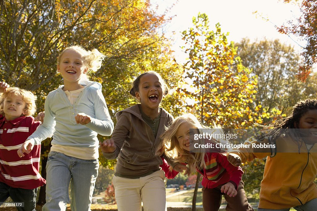 Group of children (6-7, 8-9) running in park, autumn