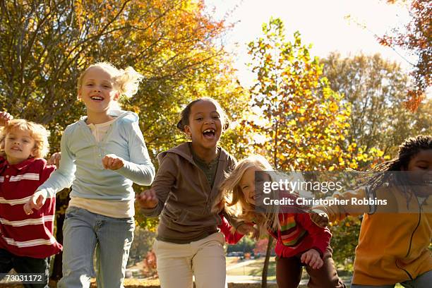 group of children (6-7, 8-9) running in park, autumn - somente crianças imagens e fotografias de stock