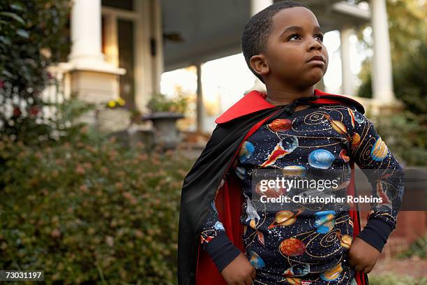boy (6-7) wearing costume standing outdoors - zwarte mantel stockfoto's en -beelden