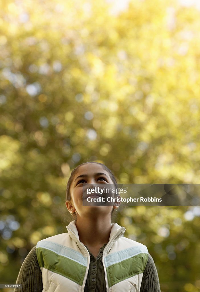 Smiling girl (10-11) looking at autumn trees