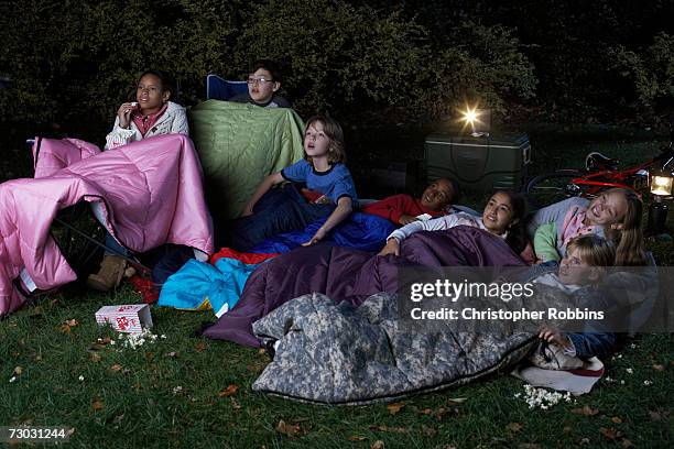 group of children (8-9, 10-11, 12-13) watching film in garden at night - cinema projector stock pictures, royalty-free photos & images