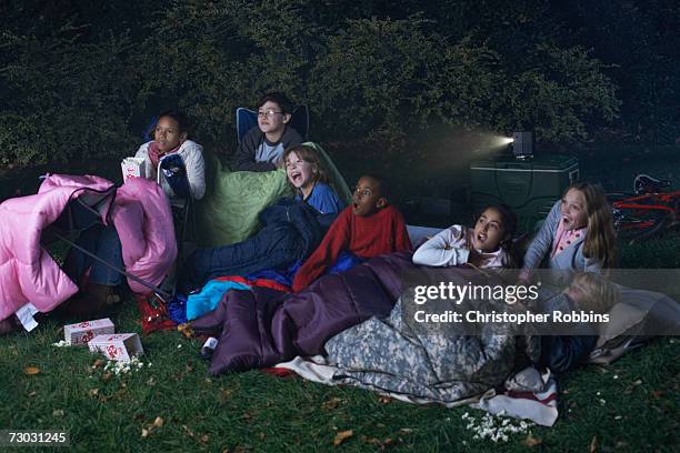 group of children (8-9, 10-11, 12-13) watching film in garden at night - mädchen 10 12 stock-fotos und bilder