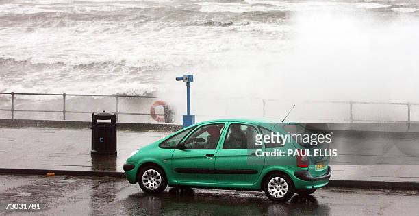 Liverpool, UNITED KINGDOM: A car is covered in sea-spray as high winds sweep through the mouth of the River Mersey at Crosby near Liverpool,...
