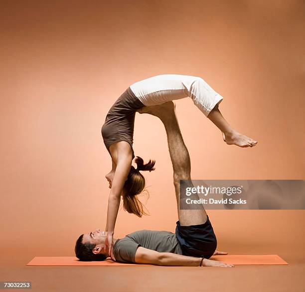 young man holding young woman in yoga pose on outstretched legs - woman straddling man stock pictures, royalty-free photos & images