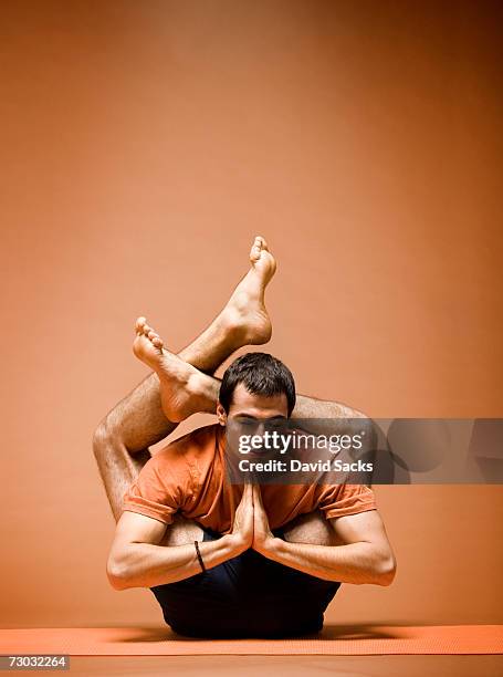 young man tangled in complex yoga pose - flexibilitet bildbanksfoton och bilder