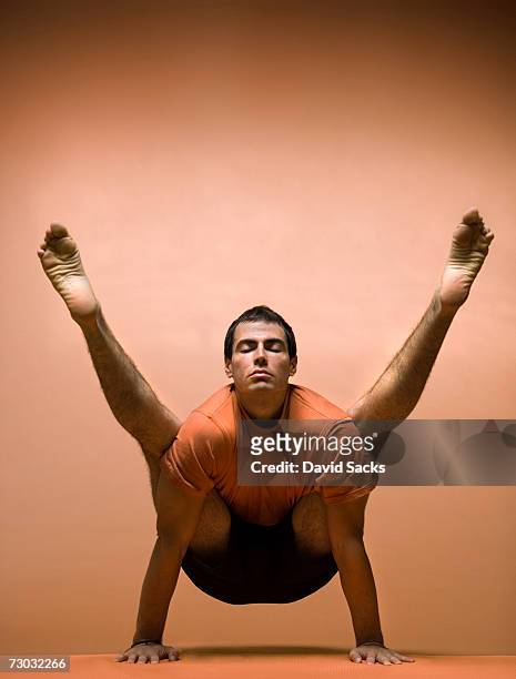 young man balancing in yoga pose, front view - legs apart imagens e fotografias de stock