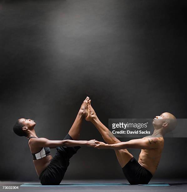 two yoga students balancing in symmetric pose, side view - gesticulando - fotografias e filmes do acervo