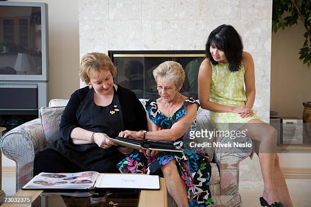 three women sitting on couch, looking at photo album - friends tv show stock pictures, royalty-free photos & images