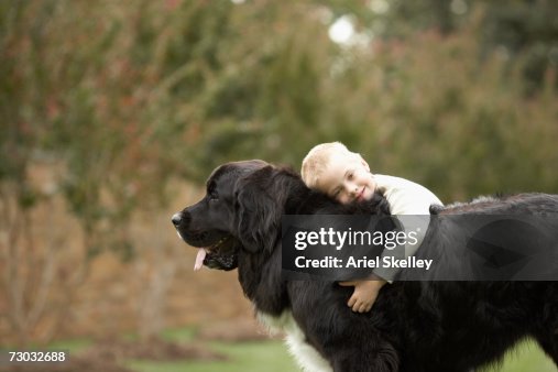 Boy (6-7) hugging black Newfoundland outdoors Boy (6-7) hugging black Newfoundland outdoors
