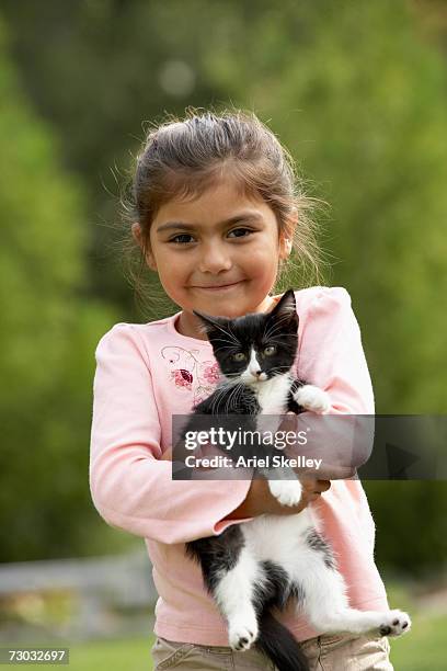 girl (6-7) holding kitten outdoors, portrait - girls cuddling cat stock pictures, royalty-free photos & images