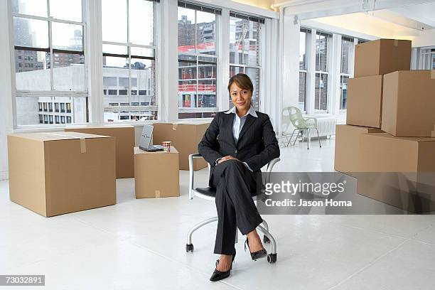 young business woman in empty office surrounded by boxes - circondare foto e immagini stock
