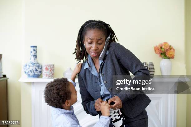 mature woman using telephone while helping son (4-5) dress up - immediate stock pictures, royalty-free photos & images