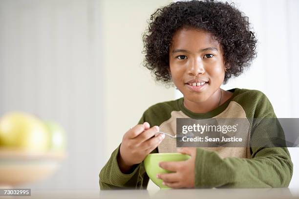 boy (10-11) eating at kitchen bench, portrait - boy eating cereal foto e immagini stock