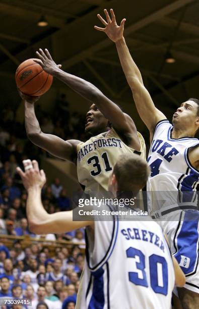 Jamie Skeen of the Wake Forest Demon Deacons shoots the ball over David McClure and teammate Jon Scheyer of the Duke Blue Devils during their game on...