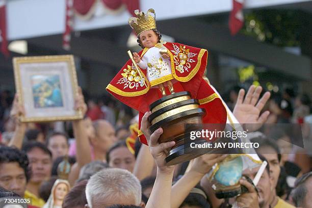 Devotees, attending a mass, raise their hands in prayer as they hold a religious icon of the Santo Nino, at the Basilica Del Santo Nino in Cebu city,...