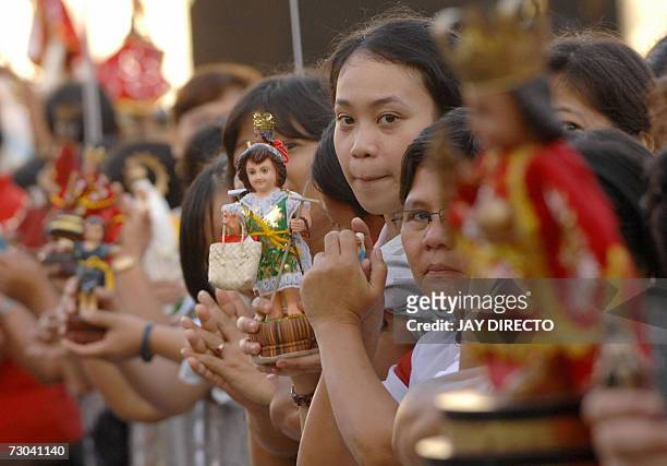 Devotees, attending a mass, hold religious icons of the Santo Nino, at the Basilica Del Santo Nino in Cebu city, 19 January 2007. The mass is part of...