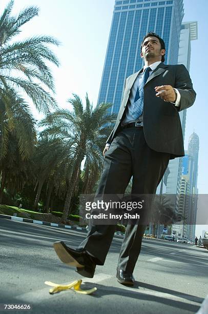 young businessman stepping on banana peel - go bananas stockfoto's en -beelden