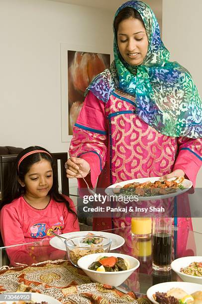 mother serving food to daughter - hot middle eastern girls stock-fotos und bilder