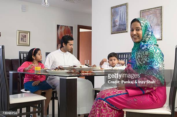 arab family of four dining while woman smiles - hot middle eastern girls stock pictures, royalty-free photos & images