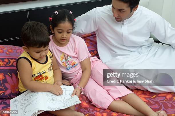 father helping children read in the bedroom - hot middle eastern girls stock-fotos und bilder