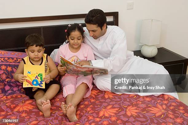 father helping children read in the bedroom - hot middle eastern girls stock-fotos und bilder