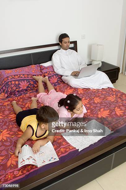 children reading on the bed while father works - hot middle eastern girls stock pictures, royalty-free photos & images