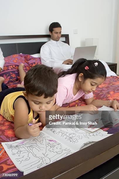 children reading on the bed while father works - hot middle eastern girls stock pictures, royalty-free photos & images