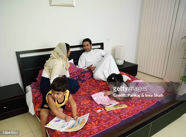 family of four playing a board game on the bed - hot middle eastern girls stock pictures, royalty-free photos & images
