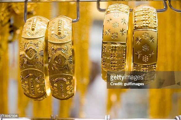 view of a gold jewelry seen from the store - armreif stock-fotos und bilder