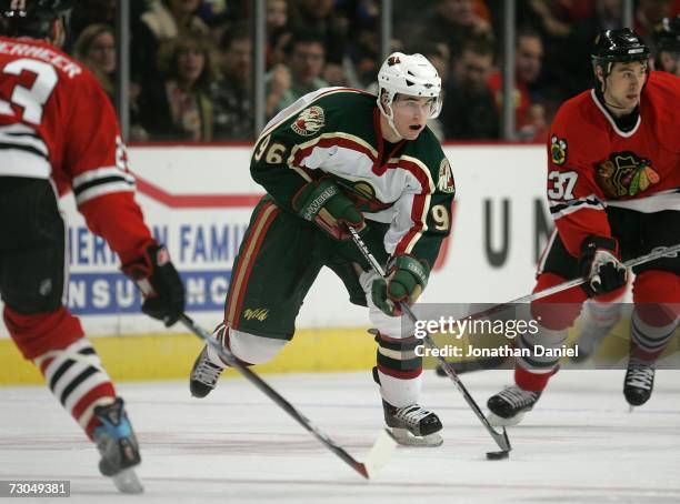 Pierre-Marc Bouchard of the Minnesota Wild controls the puck in the second period against Jim Vandermeer and Adam Burish of the Chicago Blackhawks...