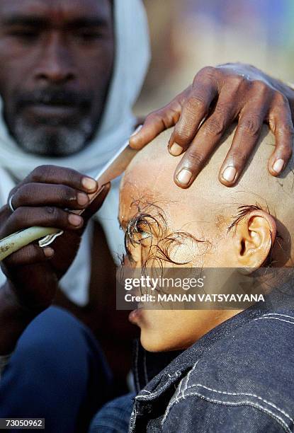 Young Indian Hindu devotee gets his head shaved on the banks of Sangam, the confluence of the Ganges, Yamuna and mythical Saraswati rivers in...