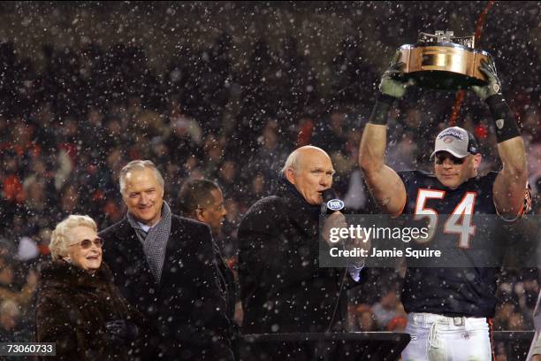 Virginia and Michael McCaskey looks on as Brian Urlacher of the Chicago Bears is interviewed by Terry Bradshaw while holding up the George S. Halas...