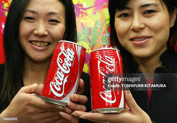 Coca-Cola Japan employees Kayo Kobayashi and Akino Sasaki hold Coca-Cola's newly designed can and the current design during the company's campaign of...