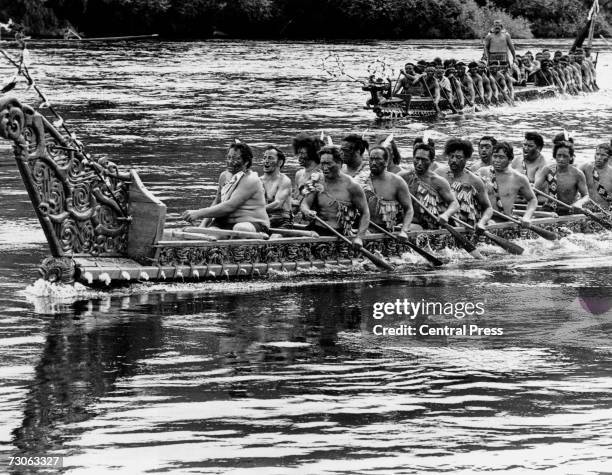 Maoris paddle down the the Waikato River in ornately carved canoes before performing for Queen Elizabeth II of Great Britain and Maori Queen Te...