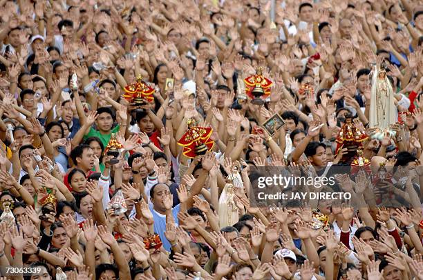 Devotees, attending a mass, raise their hands in prayer as they hold a religious icon of the Santo Nino, at the Basilica Del Santo Nino in Cebu city,...