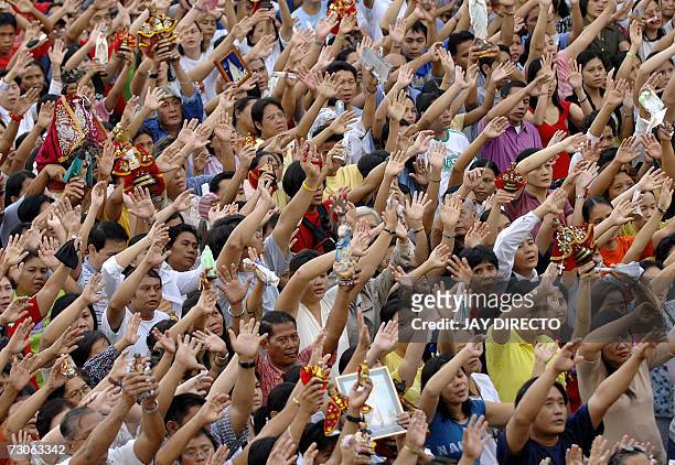 Devotees, attending a mass, raise their hands in prayer as they hold a religious icon of the Santo Nino, at the Basilica Del Santo Nino in Cebu city,...