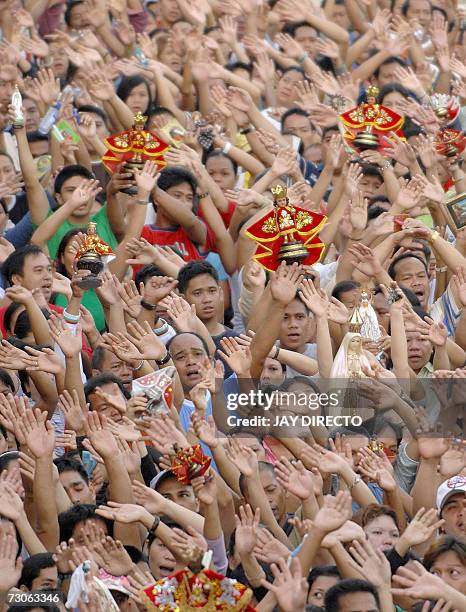 Devotees, attending a mass, raise their hands in prayer as they hold a religious icon of the Santo Nino, at the Basilica Del Santo Nino in Cebu city,...