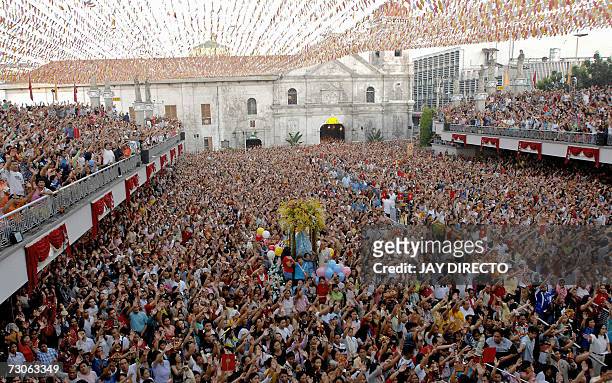 Devotees, attending a mass, raise their hands in prayer as they hold a religious icon of the Santo Nino, at the Basilica Del Santo Nino in Cebu city,...
