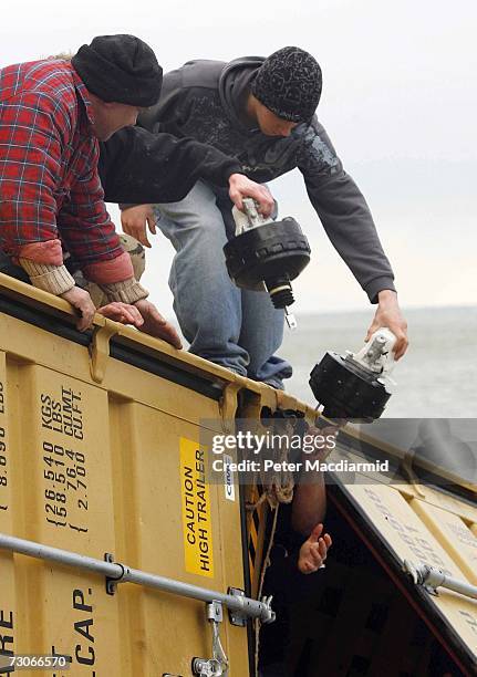 Local men take car parts from containers holding cargo from the stricken ship MSC Napoli on the beach at Branscombe on January 22, 2007 in England....