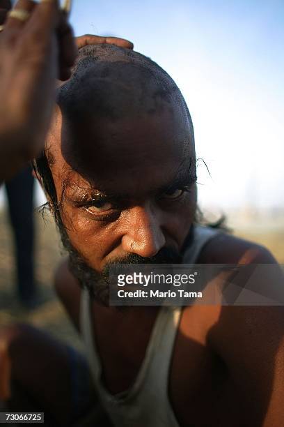 Hindu pilgrim has his head shaved in the style of a pundit at the ritual bathing site at Sangam, the confluence of the Ganges, Yamuna and mythical...