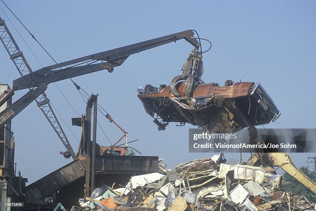 "A wrecking crane lowering a demolished automobile onto a pile of junk, Atlanta, Georgia "