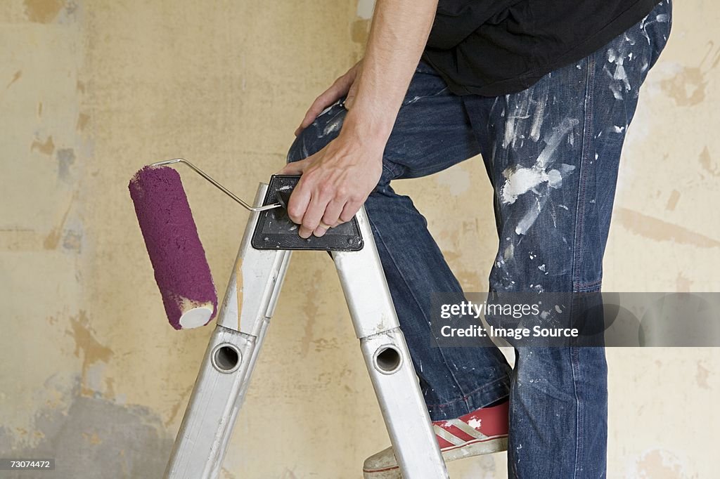 Man on stepladder with paint roller
