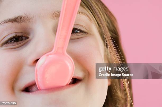 girl with plastic spoon in her mouth - mouth smirk stock pictures, royalty-free photos & images