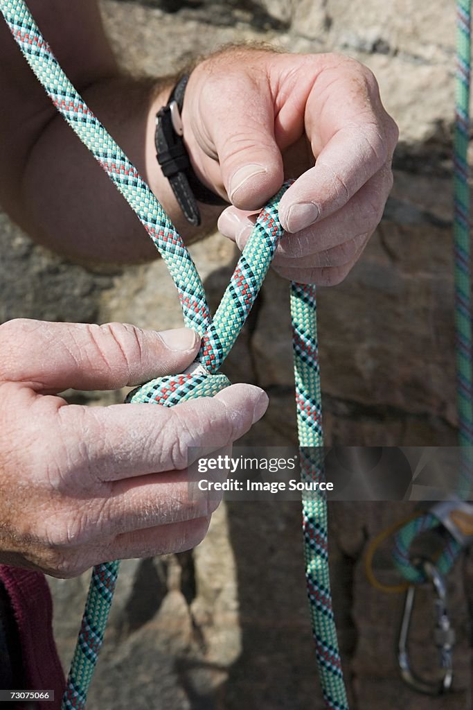 Rock climber knotting rope