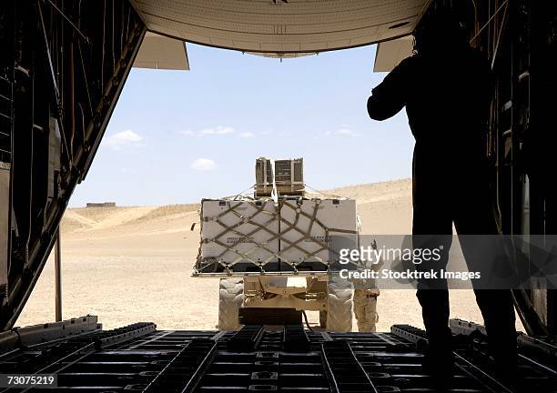 a forklift loads cargo onto a c-130 hercules on a dirt runway in tarin kowt, afghanistan, on wednesday, june 14. - c 130 hercules stockfoto's en -beelden