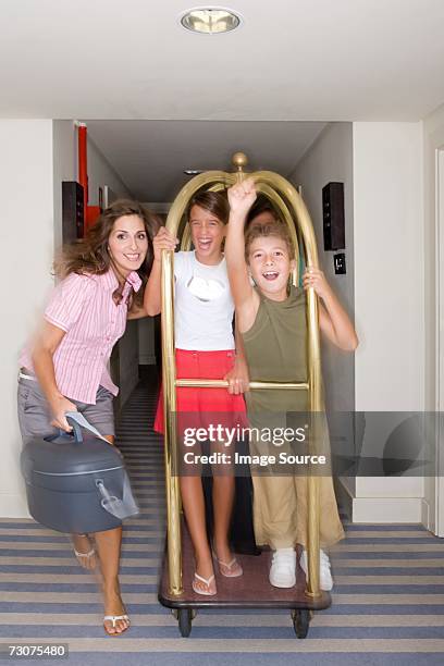 family riding a luggage trolley - hotel hallway stock pictures, royalty-free photos & images