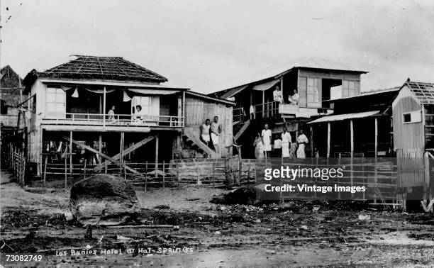 Various men and a couple of women stand around outside the ramshackle wooden Los Banos Hotel near the hot springs, Los Banos, Laguna, Philippines.