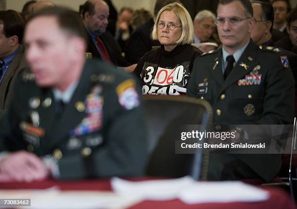 An anti-war activist sits in the audience with a death tole written on her shirt while Lt. General David Petraeus speaks during a hearing before the...