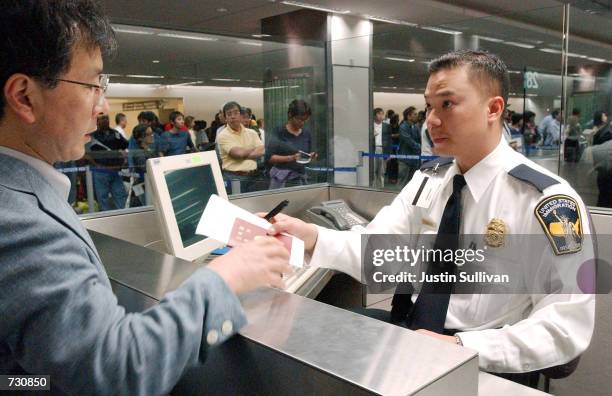 Immigration inspector Tron Nguyen processes an unidentified man going through customs at San Francisco International Airport June 14, 2002 in...