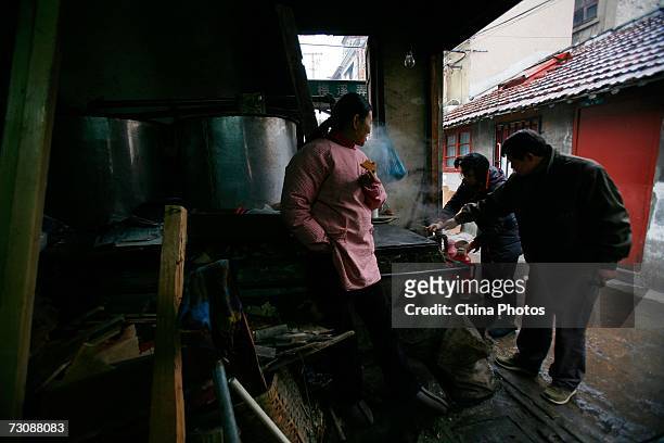 Residents buy hot water at a Laohuzao teahouse at an alleyway January 23, 2007 in Shanghai, China. Laohuzao is a traditional store which sells hot...